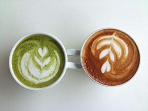 a cup of matcha latte on the left and a cup of coffee on the right with the words matcha vs coffee what is the difference?