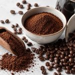 a selection of ground coffee and coffee eans in bowls and on a scoop